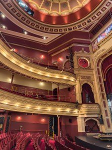 Interior view of a historic theater showcasing ornate decorations, balcony seating, and a grand stage.